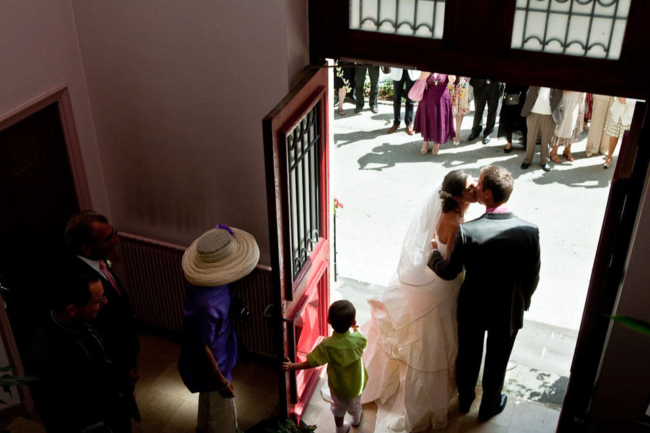 © Nicolas Gornas Photographie de mariage de la sortie de l'église quand les mariés s'embrassent